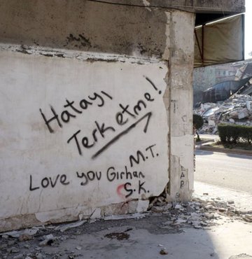 Hatay, Kahramanmaraş merkezli 7.7 ve 7.6 depremlerden sonra 6.4 büyüklüğündeki deprem sonrası enkaz kaldırma çalışmaları sürüyor. Tüm olumsuzluklara rağmen bazı kişiler, ağır hasar almayan ve gözle görülen noktalardaki duvarlara yazdıkları yazılarla moral vermeye çalışıyor.