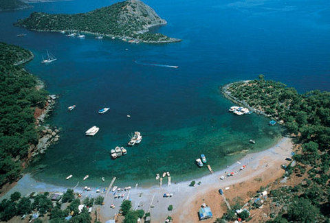 4- Fethiye'de sessizliğin adresi Gemiler: - Fethiye Ölüdeniz'in yakınında bu kadar sessiz bir yer olduğuna inanmanın güç olmasına rağmen Gemiler, etrafı çam ve zeytin ağaçlarıyla çevrili harika plajı, taze mezeler ile soğuk bira sunan birkaç güzel restoranıyla benzersiz sakin bir koydur… Sadece gezi teknelerinin değil, karayoluyla Fethiye'den Hisarönü ve Karaköy üzerinden gelen piknikçilerinde uğrak yeri olan koyun çevresinde; Soğuk Su, Kısık Koyu ve Mağarası ile Kısık Koyu`nun batısındaki Af Kale görülmeye değer gezi yerleridir. - Doğu- batı doğrultusunda başını ayakları üzerine bırakmış bir Dinozor siluetini yansıtan ve Hıristiyanlığın ilk yayılma merkezlerinden biri olması nedeni ile önem taşıyan St.Nicholas Adası (Gemiler Adası), Mavi Tur teknelerinin uğrak yeridir. 13. yüzyılın sonlarına kadar Bizanslılar'ın elinde olan, daha sonra şövalyelerin eline geçen adada, kilise, manastır, şapel gibi dini yapıların kalıntıları vardır. Deniz kıyısında sarnıç, tepe bölümünde ise saray kalıntıları yer alan adanın, tarihten önemli izlerin bir kısmı da sular altındadır.