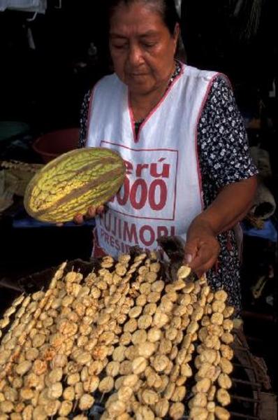 Peru Loreto'da elinde meyve tutan bir satıcı çekirdek kavururken.