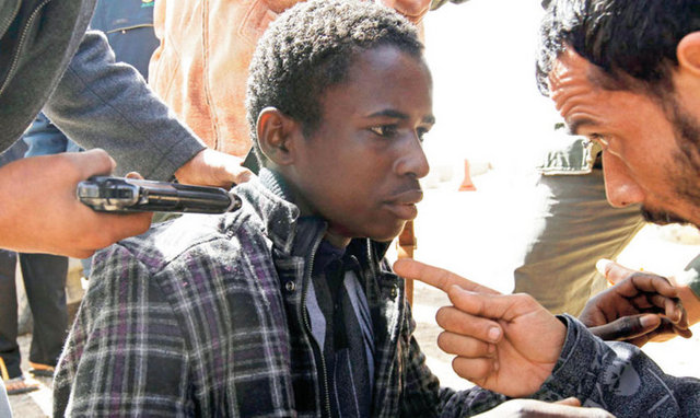 Hayat bir giysi kadar ucuz - Kaddafi yanlısı olmakla suçlanan yaşı 20'ye varmamış bir - genç. İsyancıları kuşkulandıransa üzerindeki şık giysiler. - Libya'nın Brega ve Ras Lanuf kentleri arasında bir yerde başına - doğrultulmuş bir silah eşliğinde sorgulanıyor. Tarih: 3 Mart.