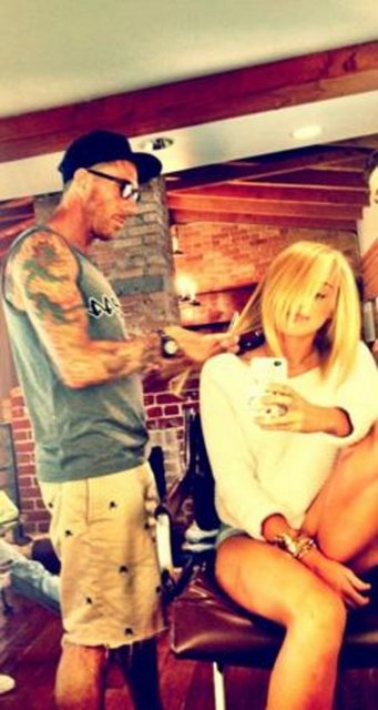 Cyrus kuaför koltuğunda otururken bile elinde cep telefonuf var.