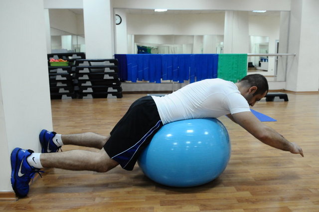 3-Ayaklarımızı duvara dayayarak yüzüstü pilates topuna uzanıp ellerimizi ileride birleştirip sırtımızı geriye doğru sıkıştırıp dirseklerimizi arkaya doğru alıyoruz.
