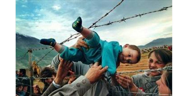 2000 Carol Guzy -  - Pulitzer ödüllü bir fotoğraf daha. 2 yaşındaki Agim Shala, Birleşik Arap Emirlikleri'nin Arnavutluk'ta kurduğu kampta dikenli teller üzerinden büyük anne ve büyük babasının ellerine teslim ediliyor...