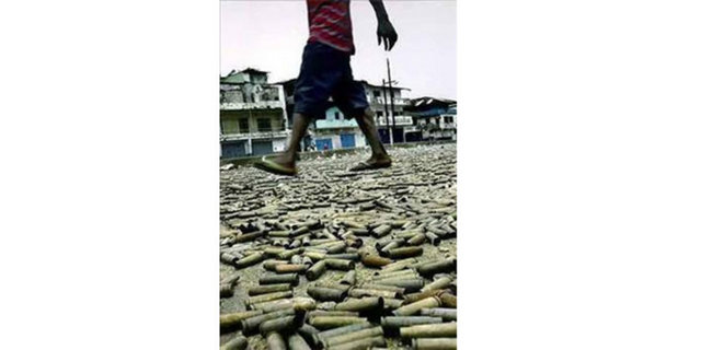 2004 Calorilyn Cole -  - Liberya'nın başkenti Monrovia'da çekilen bu kare hükümet yanlıları ile asiler arasında yaşanan çatışmadan arta kalan mermiler üzerinde hiç bir şey olmamış gibi dolaşan bir genci görüntülüyor...