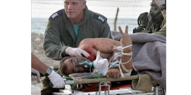 AFP -  - Güney Lübnan'da yaralanan İsrail askeri hastaneye giderken gazetecilere zafer işareti yapıyor...