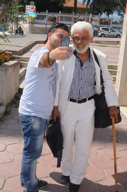 Gedik'i tanıyanlar, birlikte fotoğraf çektiriyor. Gedik, kitaplarını imzalayarak satıyor.