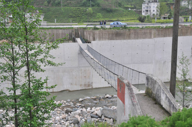 Rize'de Taşlıdere üzerinde 60 metre uzunluğundaki asma köprü, yapımı devam eden duble yol inşaatı kapsamındaki istinat duvarı ile ikiye bölününce, ortaya ilginç bir görüntü çıktı