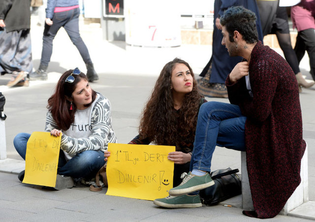  Kent merkezindeki İsmetpaşa Caddesi'nde kaldırıma oturarak derdini anlatmak isteyenlerle 1 lira karşılığında görüşen Uşak Üniversitesi Fen Edebiyat Fakültesi Sanat Tarihi Bölümü öğrencisi Fatma Kübra Çavuş ile İletişim Fakültesi Radyo Televizyon ve Sinema Bölümü öğrencisi Büşra Bayer, vatandaşlardan ilgi görüyor.