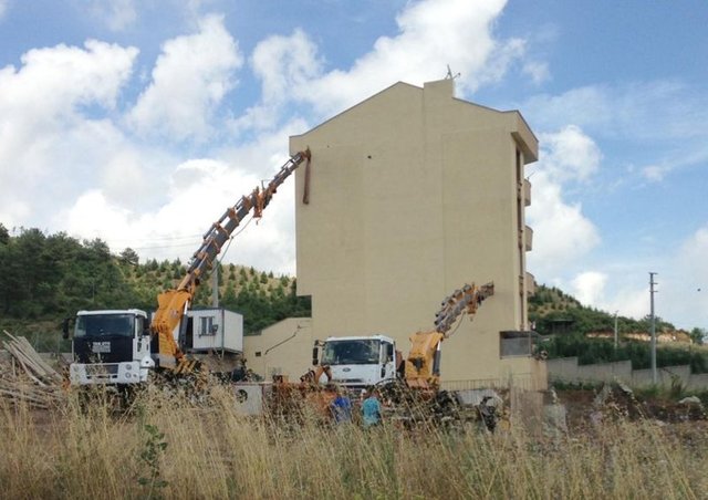 Durumu fark eden müteahhit, apartmanın yan yatmaması için çareyi 2 vincin kollarını binanın duvarına destek yapmakla buldu.