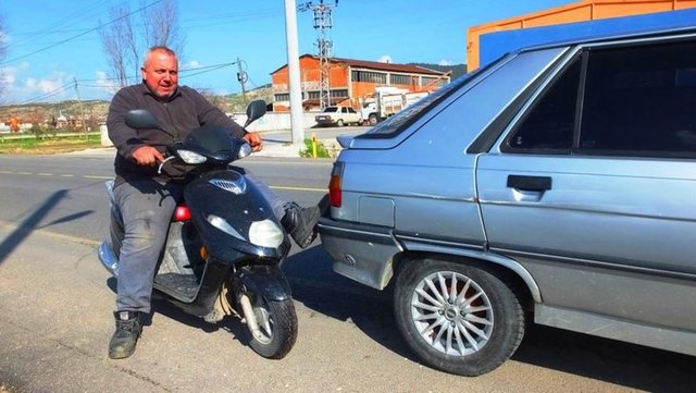 BU ANCAK TÜRKİYE'DE OLUR! - Motosikletinin direksiyon başına geçen Kırbaş, yolda kalan araçları ayağıyla iterek akaryakıt istasyonuna kadar götürüyor.