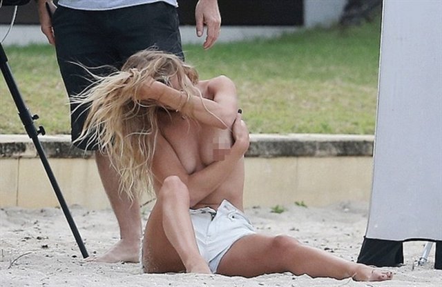 Sadece minik beyaz şortuyla kumsalda poz veren Rosie Huntington göğüslerini elleriyle kapatsa da arada frikik vermekten kaçamadı.