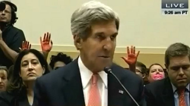 Oturumun yapıldığı salonda protestocular, kırmızıya boyadıkları ellerini havaya kaldırdı.