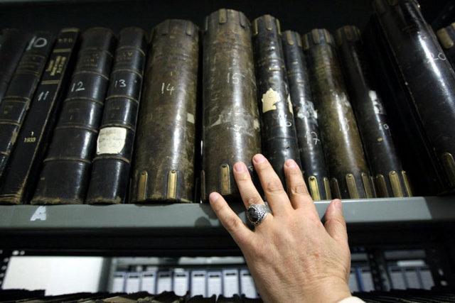 Dağ gibi yükselen evrakların çoğunluğu Osmanlıca, bir kısmı da Türkçe. Zarar görmemesi için belgelere gömlek giydiriliyor.