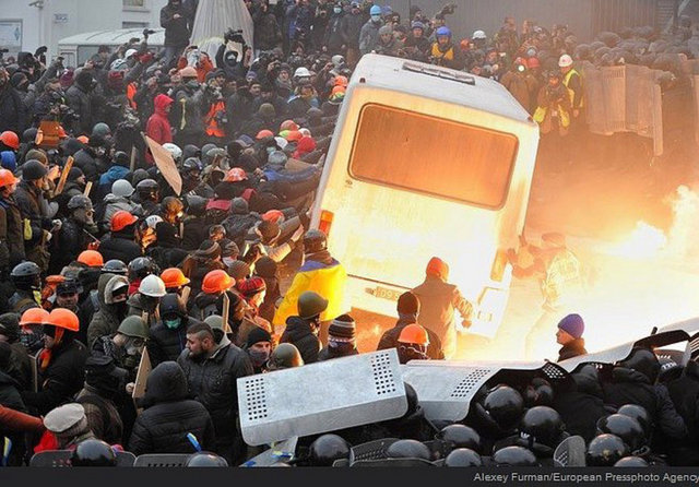 Protestocular bir otobüsü devirmeye çalışırken.