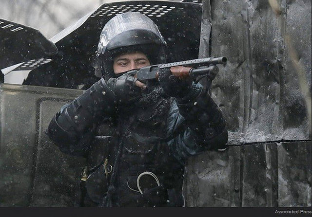 Ukrayna'nın başkenti Kiev'de hükümet karşıtı gösteriler sürüyor. Bir polis elindreki tüfeği protestoculara doğrulturken.