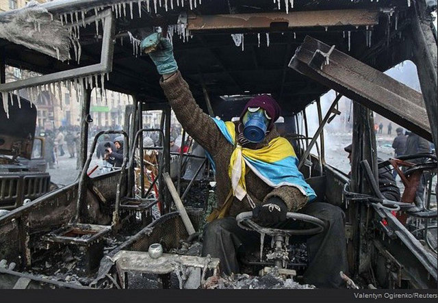 Yanmış bir otobüsün içerisinde bir protestocu.