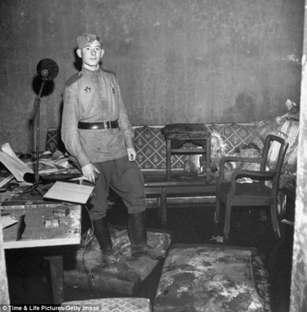 Sığınağın bir diğer odasındaki molozların arasında, yırtık ve yanmış kanepenin önünde bir Rus askeri.