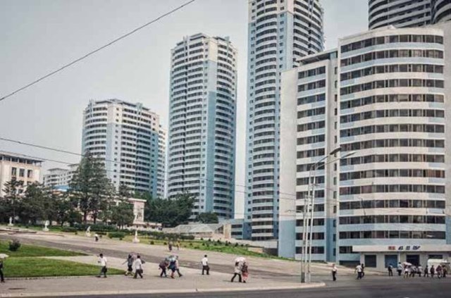 Pyongyang kentinde gökdelenler önünde yürüyen insanlar