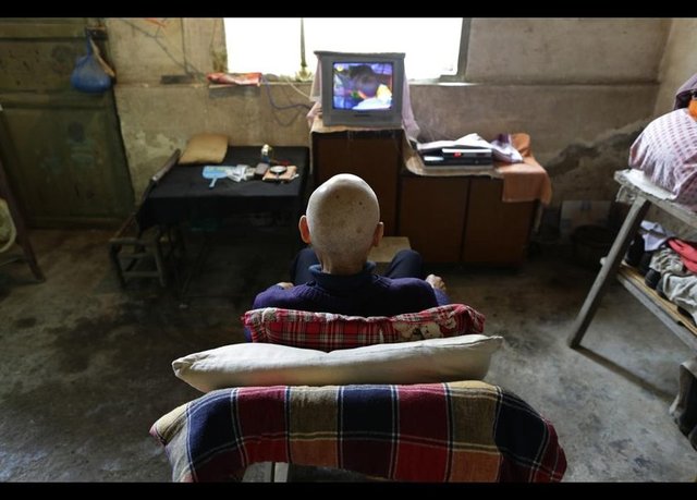 Deri kanseriyle savaşan 82 yaşındaki Qin Wenji, oturma odasında televizyon seyrediyor. -