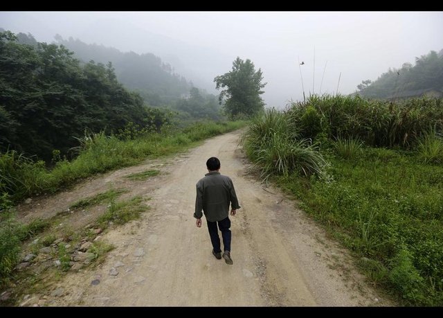 61 yaşındaki Xiong Dejun da akciğer kanseriyle mücadele edenlerden... Xiong, kendisini röntgen muayenesi için hastaneye götürecek otobüs durağına yürüyor. -
