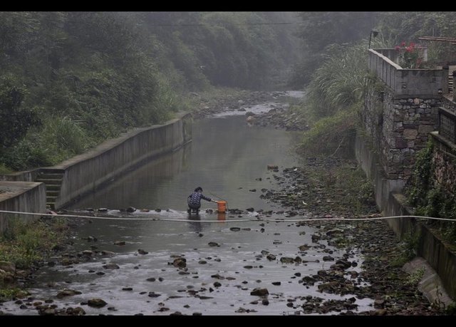 -  - Heshan köylülerinden bir kadın çamaşır yıkıyor. Bölgedeki sanayi atıkları toprak dışında suyu da kirletiyor. Sadece arsenik değil kurşun oranı da yüksek seviyede.