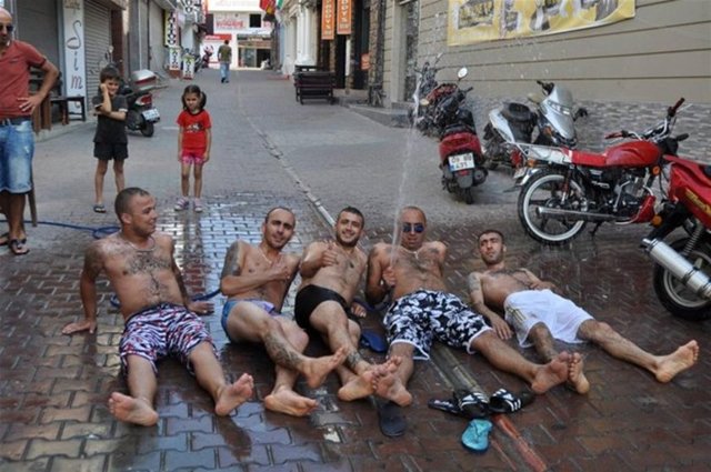 Birbirlerine tuttukları hortumla serinleyen bar çalışanları, fırça ve sıvı sabunla yıkanmaya başlayınca, kendilerini izleyen tatilci ve turistleri gülümsetti.