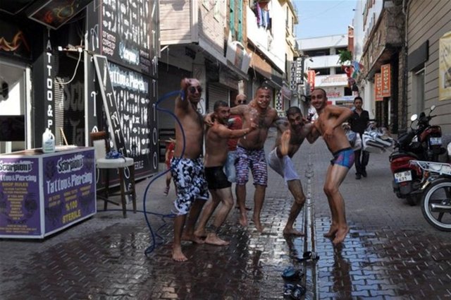 Aydın'ın Kuşadası İlçesi'nde sıcak havadan bunalanlar serinlemek için çeşitli yol ve yöntemler deniyor. Kuşadası Barlar Sokağı çalışanları, hortum ve temizlik fırçasıyla serinlemeye çalıştı.