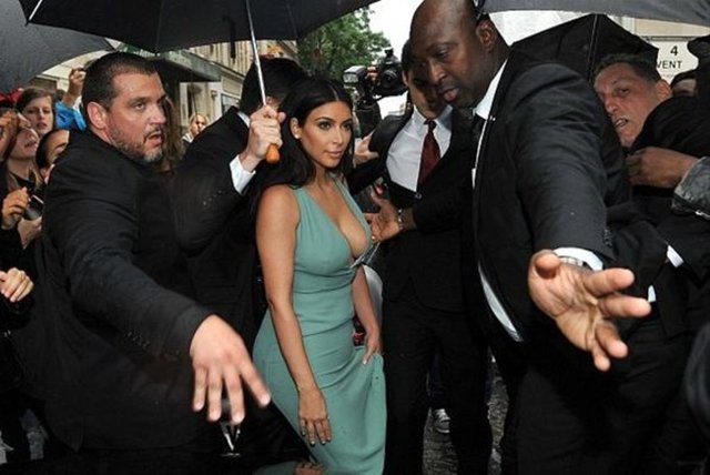 Yağmura yakalanan Kardashian'ın giydiği derin dekolteli turkuaz elbise ıslanmasın diye korumalar seferber oldu.