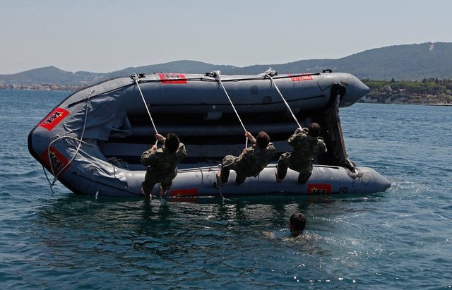 Yaklaşık 7 metrelik kulelerden atlayan öğrenciler, bot devirme, savaş yüzmesi ve koordineli kürek çevirme görevlerini tamamlıyorlar.