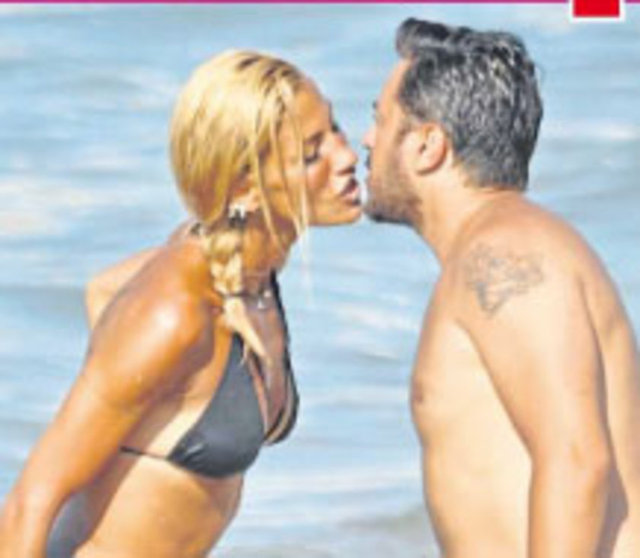 Meraklı bakışlara aldırmadan bol bol öpüşen çift, daha sonra oğullarıyla denize girdi.