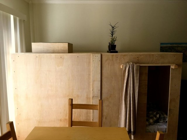 Odada yatak, katlanır masa, kitap-giysi rafları ve ışıklandırma bulunuyor.