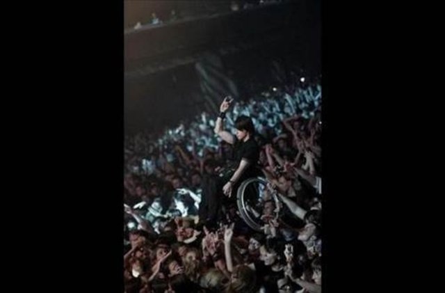 Kalabalık, konserde tekerlekli sandalyeli genci, sahneyi rahat görmesi için havaya kaldırırsa.