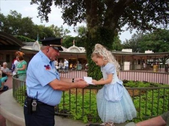 Magic Kingdom oyun parkında güvenlik görevlilerinden biri, prenses gibi görünen küçük kızdan imza isterken.