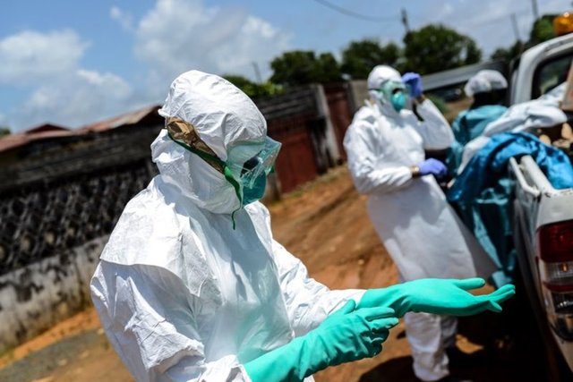 Görevliler, John'un cesedini evinden çıkarma işlemi öncesi koruyucu elbiselerini böyle giydi.  -