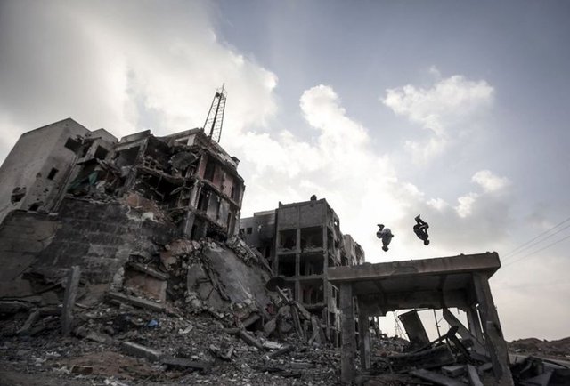 Filistinli gençler, Gazze'nin kuzeyindeki Beyt Lahya kentinde İsrail saldırıları nedeniyle yıkılan evler arasında parkur sporunu icra ediyor.  - 18.10.2014