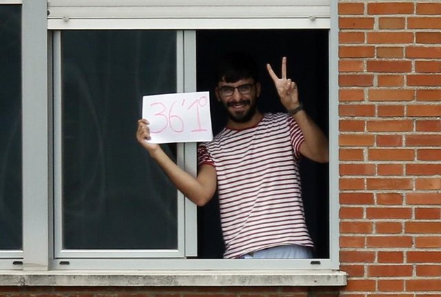 Kimliği belirlenmeyen bir adam, Ebola'ya yakalanan İspanyol hemşirenin kaldığı Madrid's Carlos III Hastanesi'nin izole edilmiş 5. katında bulunan odasının penceresinden, işaret ile vücut ısısının olduğu 36 C derece (ya da 97 Fahrenheit) olduğunu göste