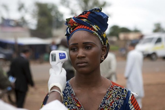 Bir sağlık çalışanı Kouremale sınırında, Gine'den Mali'ye giren bir kadının ateşini kontrol ediyor. (Mali, 2 Ekim 2014, REUTERS/Joe Penney)