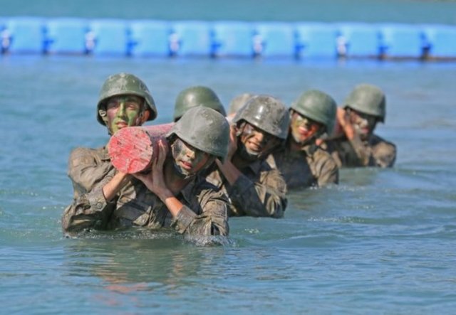 Denizde kütük taşıyan tim üyeleri, kuleden eğitim elbiseleriyle denize atladıktan sonra, güç kazanmak ve bitirme sevincini zirveye ulaştırmak için deniz için eğitim elbiseleriyle parkur andı içiyorlar.