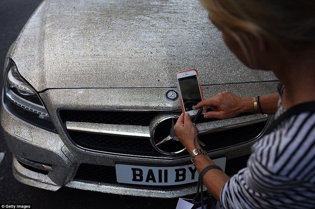 Yoldan geçen bir kadın lüks Mercedes'in fotoğraflarını çekiyor.  -