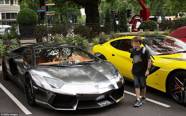 Küçük çocuk, Londra meydanında bir otoparkta gördüğü metalik Lamborghini'yi hayranlıkla izliyor.  -