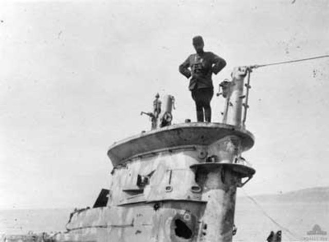 Bir Türk askeri ele geçirilen İngiliz denizaltısının üzerinde poz veriyor.