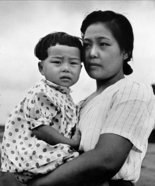 Bir anne ve çocuğu, kurbanların aileleri için yardım toplanan Shinto tapınağında görülüyor.