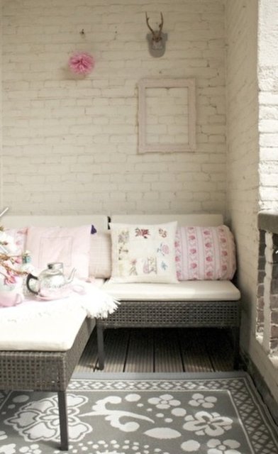 20- Beyaza boyanmış tuğla duvarlar ve pembe detaylı aksesuarlar ne kadar romantik görünüyor. Çiçekli minderler, çiçek desenli kilim, duvardaki minik aksesuarlar balkona feminen bir hava katıyor.