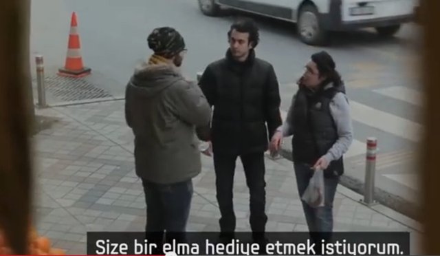 Vatandaş işaret diliyle teşekkür ederek onlara elma ikram etmek istediğini söylüyor.