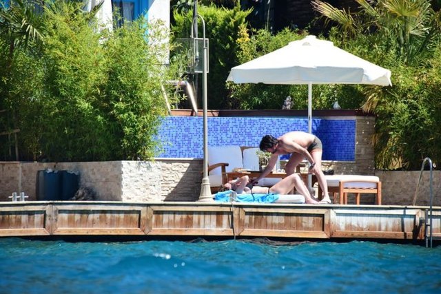 Şezlonguna uzanan Abdullah'ın vücuduna özenle güneş yağı süren Tiryaki, ortaya ilginç karelerin çıkmasına neden oldu.