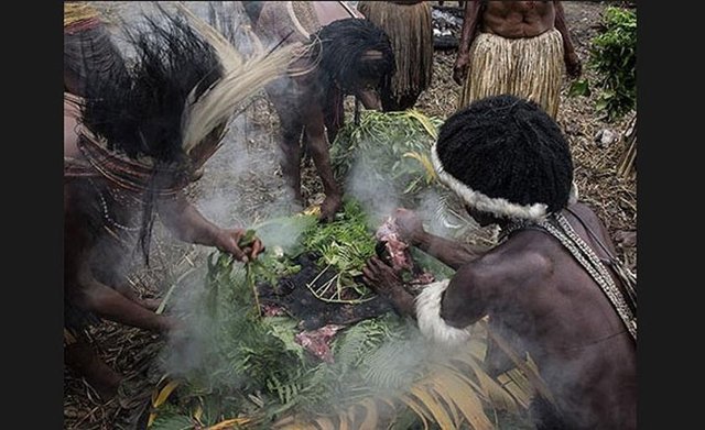 Yerliler sebzeli domuz eti pişiriyor.