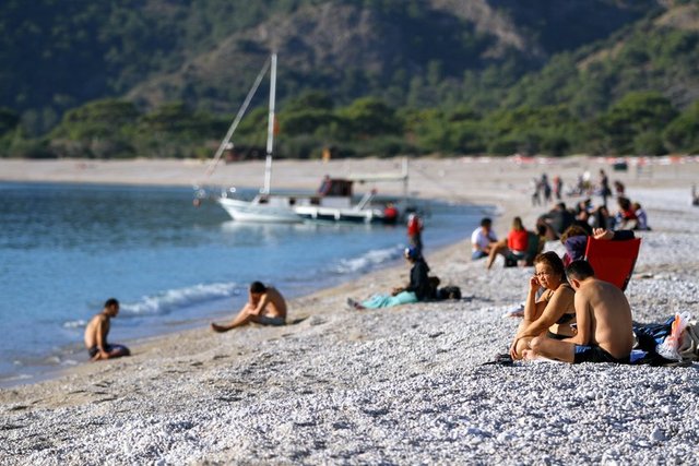 Hava sıcaklığının 19, deniz suyu sıcaklığının ise 20 derece ölçüldüğü Fethiye'de hafta sonu tatilini fırsat bilen vatandaşlar, Ölüdeniz Mahallesi'ndeki Belcekız Plajı'nda denize girdi, kumsal da güneşlendi.