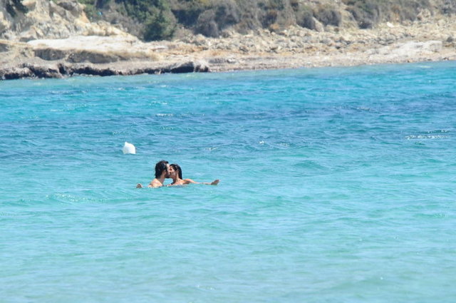 Baş başa kalmak için sakin bir koyu tercih eden çifte kumrular, etrafta kimsenin olmadığını düşünüp denizin içinde uzun uzun öpüştü. 