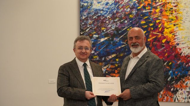 PROF. DR. M. NECMETTİN ATSÜ SANATÇI DENİZHAN ÖZER'E PLAKETİNİ TAKDİM ETTİ.