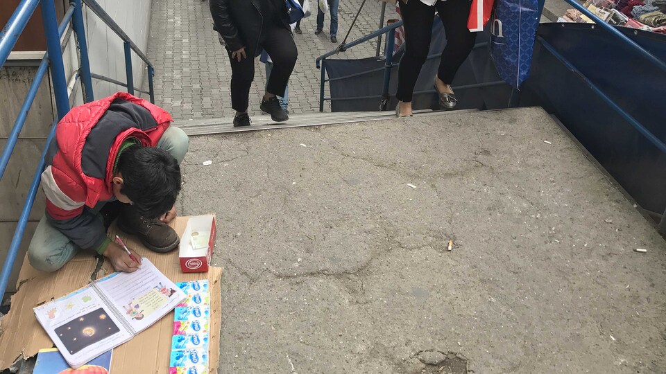 Savaştan kaçan Afgan çocuk, ödevini mendil satarken yapıyor